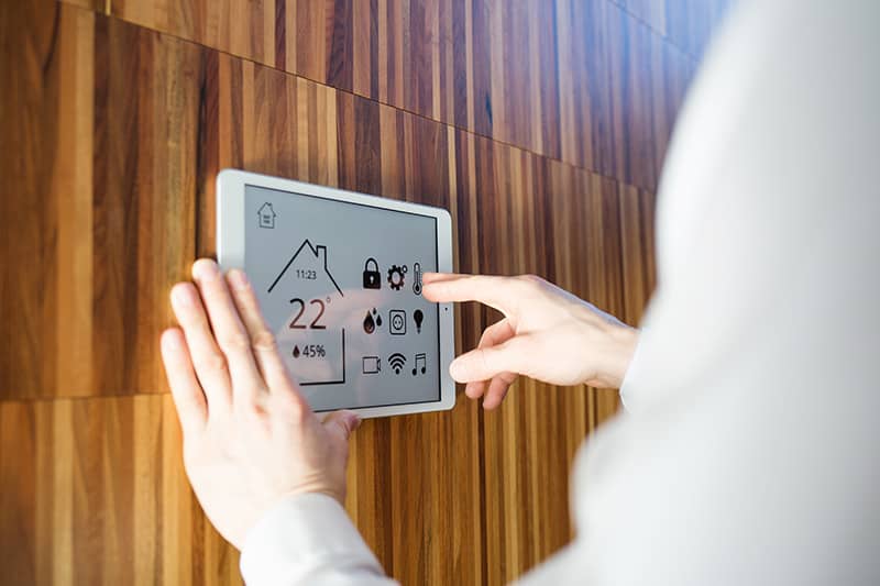Woman adjusting the climate temperature on digital thermostat for her home.