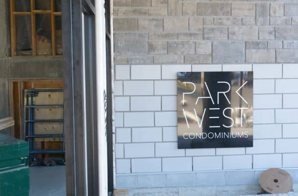 Sign of Park West Condominiums against a brick wall.