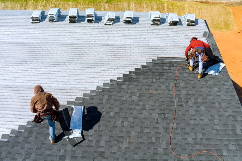Workers replacing roof tiles on a home.